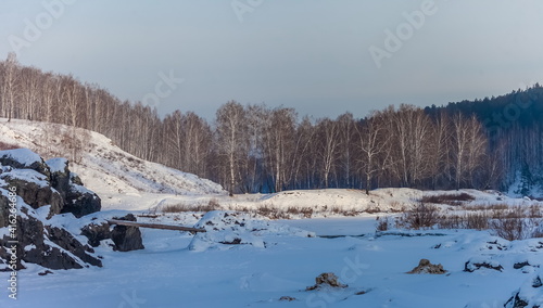 Winter landscape with frozen river, snow, rocks and trees © Александр Коликов