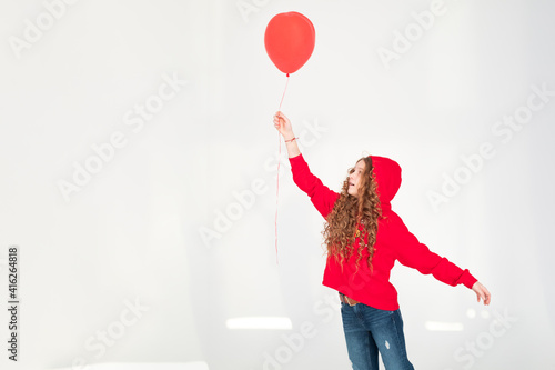 Part body size view of nice attractive, funny cheerful teenage kid girl holding in hand red air balloon having fun on white grey background. Copy space. Celebration concept photo