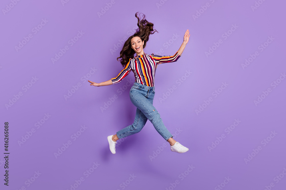Full length body size photo of pretty girl jumping up childish playful with flying in air hair isolated vivid purple color background