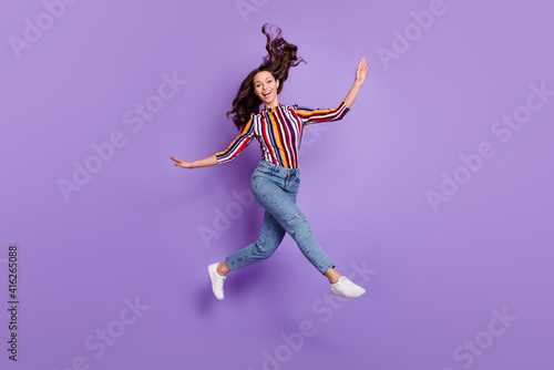 Full length body size photo of pretty girl jumping up childish playful with flying in air hair isolated vivid purple color background