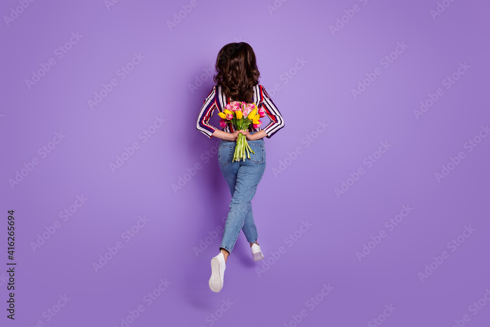 Rare view full length body size photo of woman jumping running holding tulips isolated vibrant purple color background Rare view full length body size photo of woman jumping running holding tulips isolated vibrant purple color background