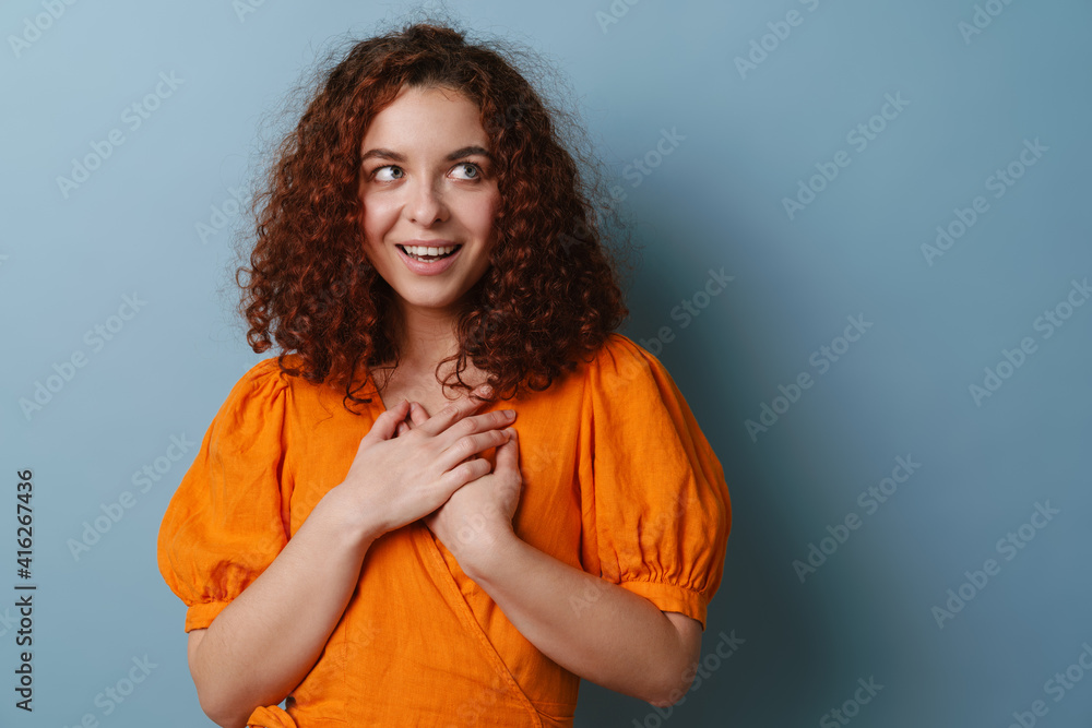 Happy redhead curly girl posing with hands on her chest Happy redhead curly girl posing with hands on her chest