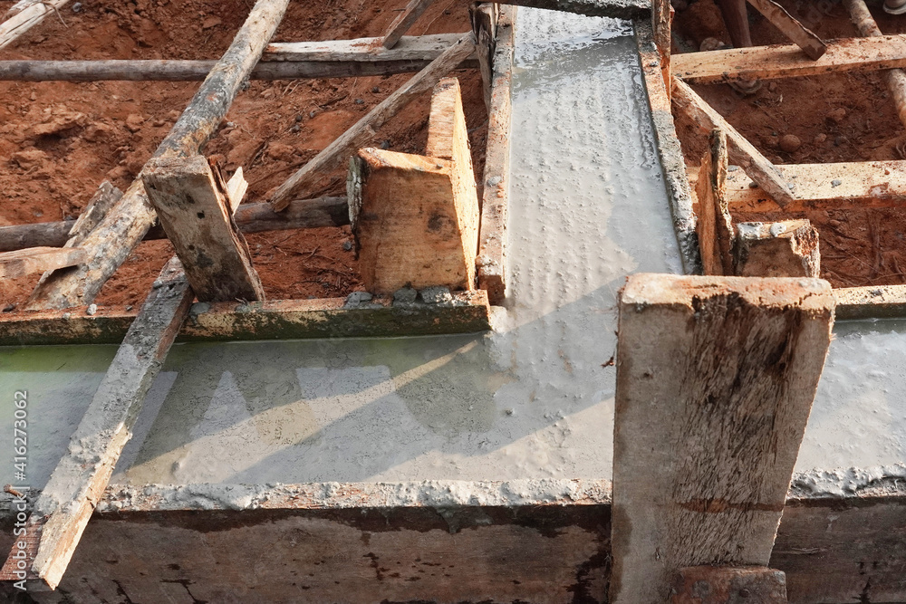 Concrete poured into wooden mold containing rebar, wide angle view. This becomes the foundation of a house. Concrete poured into wooden mold containing rebar, wide angle view. This becomes the foundation of a house.