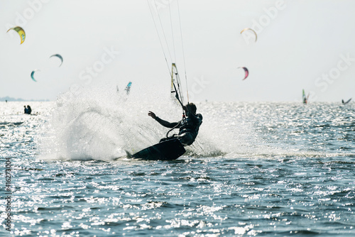 People swim in the sea on a kiteboard or kitesurfing. Summer sport learning how to kitesurf. Kite surfing on Puck bay in Jastarnia, Poland photo