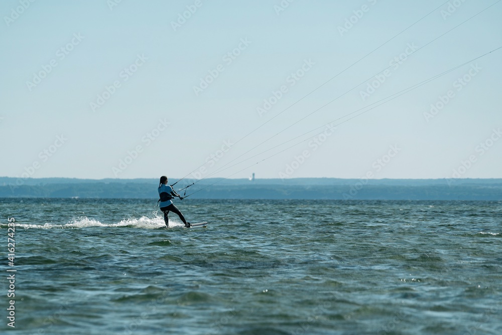 People swim in the sea on a kiteboard or kitesurfing. Summer sport learning how to kitesurf. Kite surfing on Puck bay in Jastarnia, Poland