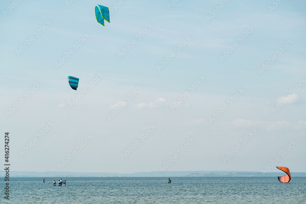 People swim in the sea on a kiteboard or kitesurfing. Summer sport learning how to kitesurf. Kite surfing on Puck bay in Jastarnia, Poland