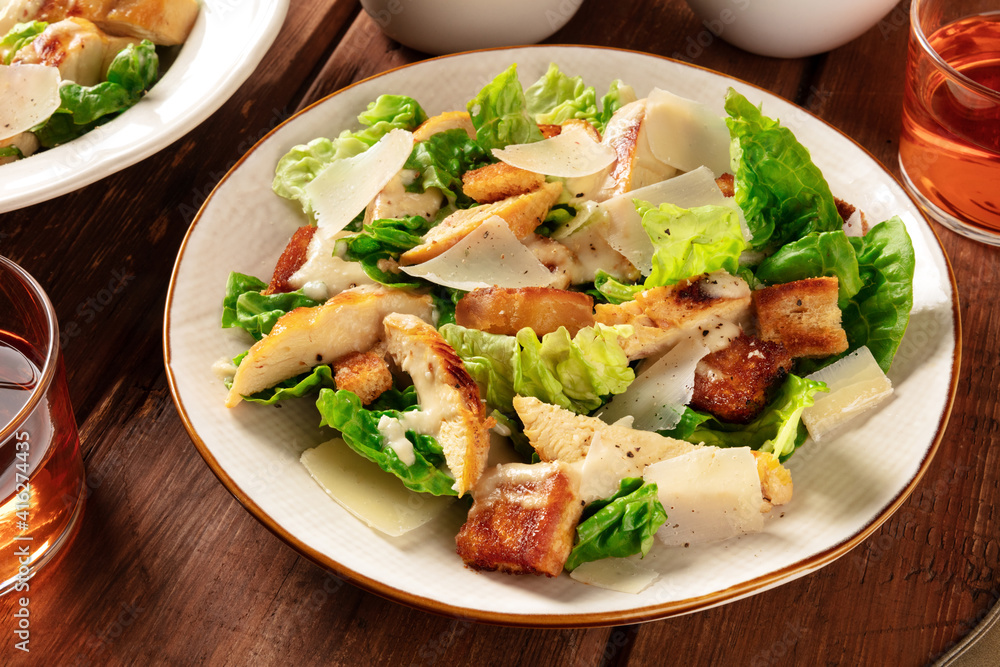 Caesar salad close-up. Grilled chicken breast slices, green romaine salad leaves, croutons and Parmesan, the classic recipe Caesar salad close-up. Grilled chicken breast slices, green romaine salad leaves, croutons and Parmesan, the classic recipe