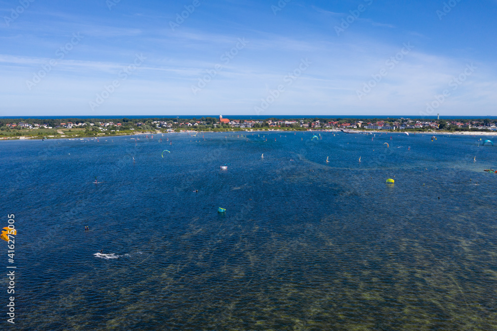People swim in the sea on a kiteboard or kitesurfing. Summer sport learning how to kitesurf. Kite surfing on Puck bay in Jastarnia, Poland, Europe aerial drone photo