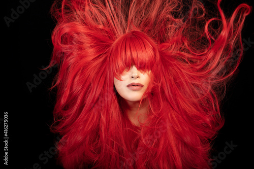 Canvas Print Hair care and styling concept with a beautiful young woman with her face framed by flying long red hair over a black background in a close up portrait