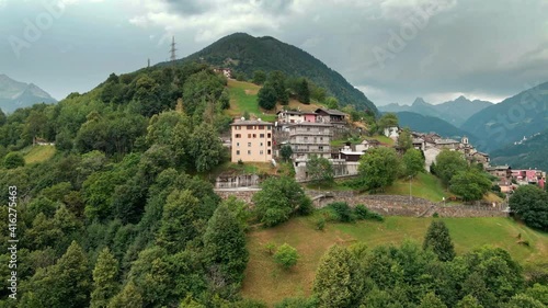 Hillside buildings and houses in a small village in Italian Alps. Aerial view of Bema comune, Sondrio province, Italy under stormy sky on spring season, drone shot photo
