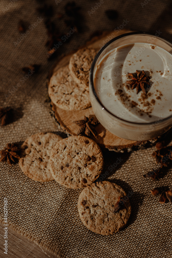 Beautiful creamy coffee in a cup with cookies and brownies carefully placed on the wooden surface with a brown background covered with beams of sunlight Beautiful creamy coffee in a cup with cookies and brownies carefully placed on the wooden surface with a brown background covered with beams of sunlight