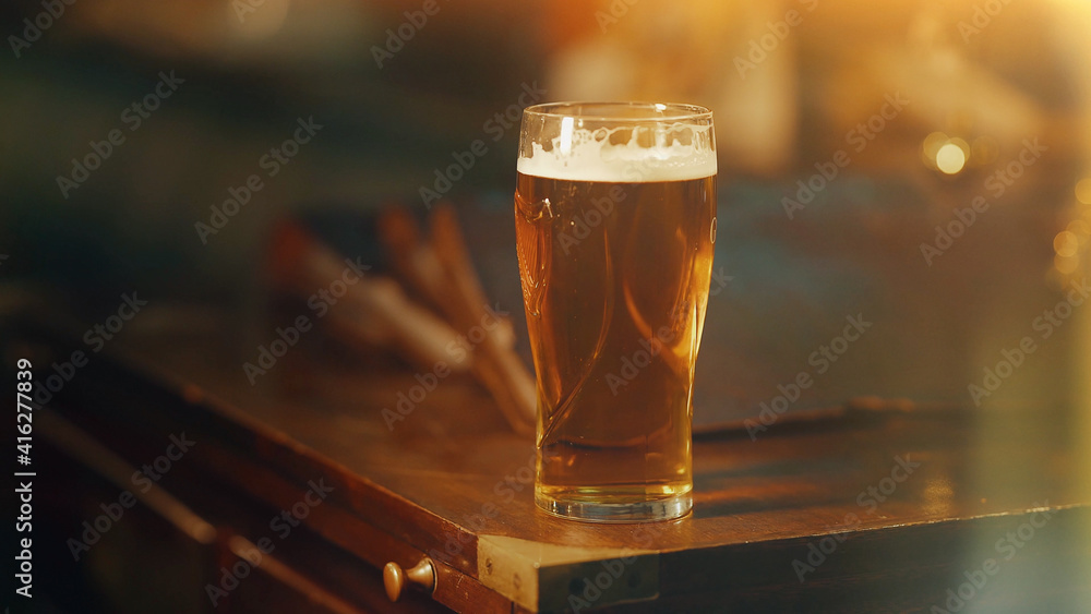 Glass of beer on wooden old table. Rustic Wood Table Bar. Cold light beer on a dark background. Depth of field Glass of beer on wooden old table. Rustic Wood Table Bar. Cold light beer on a dark background. Depth of field