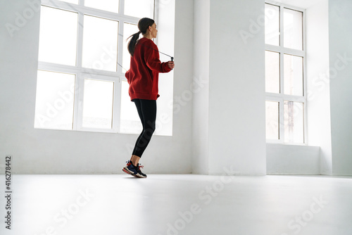 Athletic young sportswoman working out with jumping rope