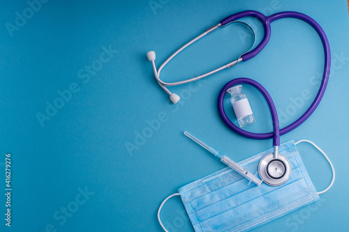 Medical check up concept. Top view medical equipment on blu background. Flat lay surgical mask, stethoscope, pills, syringe, thermometer, gloves and clipboard. Medical banner design template. 