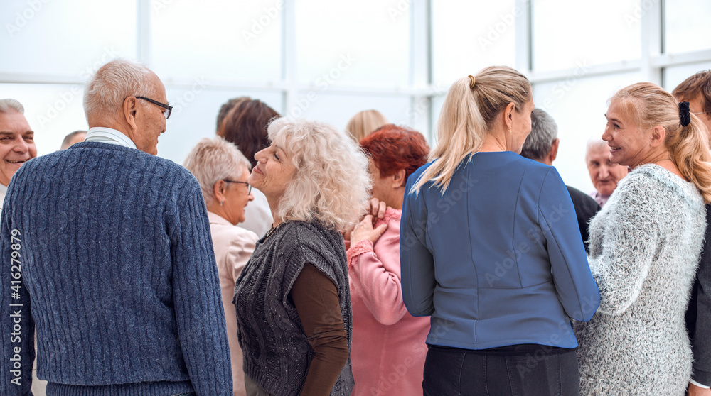 a group of old people standing with their backs indoors a group of old people standing with their backs indoors