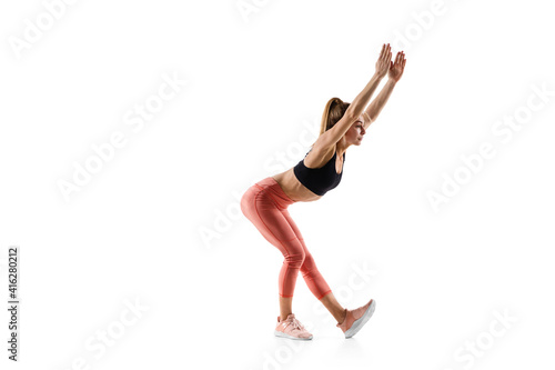 Stretching. Young caucasian female model in action, motion isolated on white background with copyspace. Concept of sport, movement, energy and dynamic, healthy lifestyle. Training, practicing.