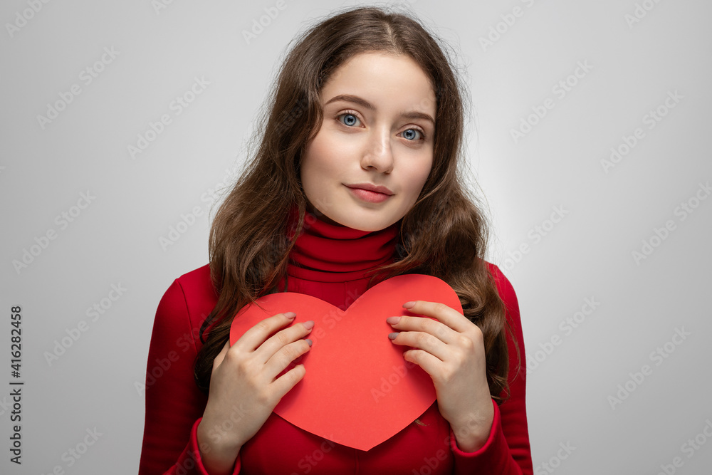 Young girl showing red heart from cardboard to camera Young girl showing red heart from cardboard to camera