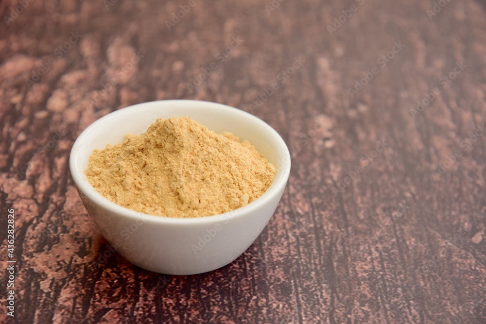 Bowl of maca powder on wooden background Bowl of maca powder on wooden background