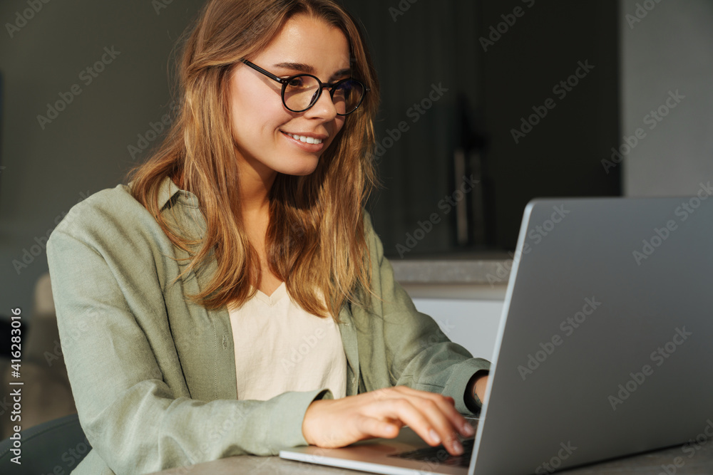 Happy nice woman smiling and working with laptop while sitting at home Happy nice woman smiling and working with laptop while sitting at home