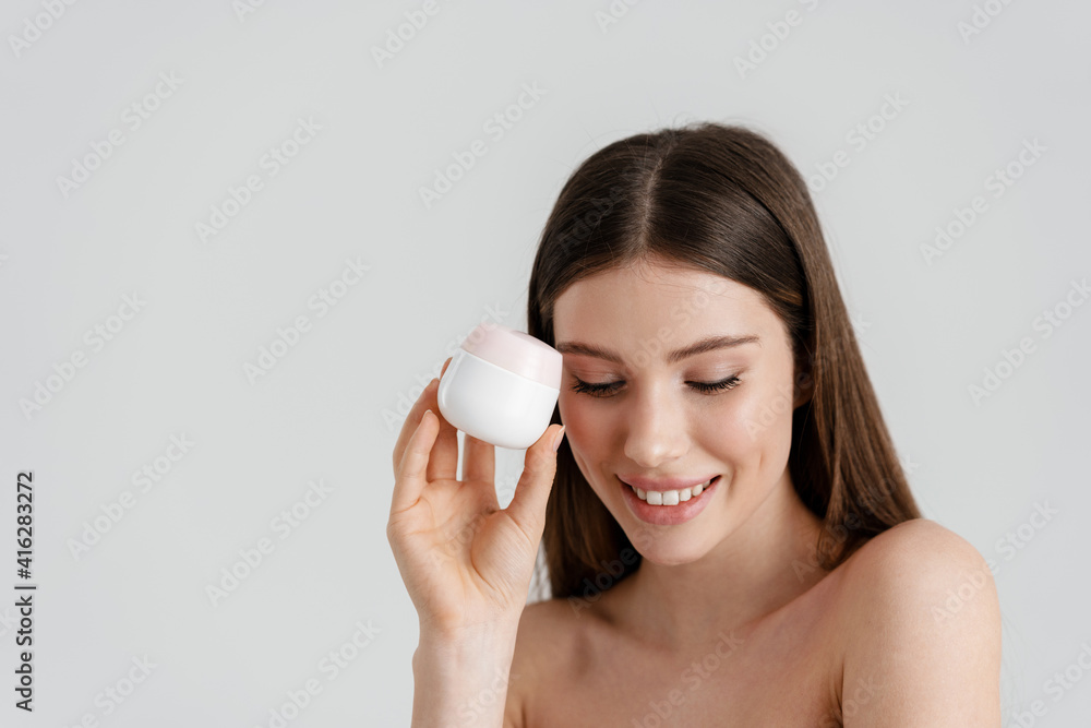 Happy shirtless nice girl smiling while posing with facial cream Happy shirtless nice girl smiling while posing with facial cream