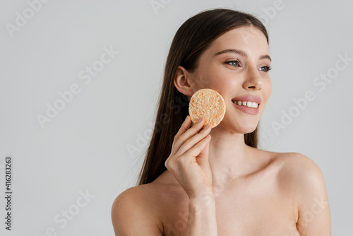 Happy shirtless nice girl smiling while using cleansing sponge