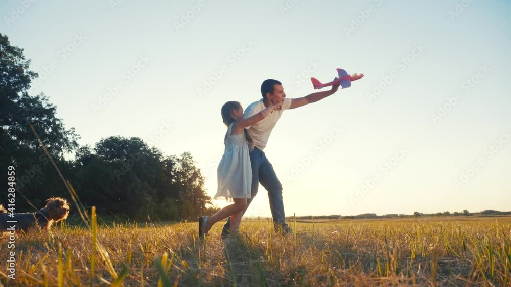 dad and daughter play with a toy airplane in the park in nature with a dog. kid dream concept happy family. dad and daughter play outdoors in the park. happy family with dream dog airplane in nature dad and daughter play with a toy airplane in the park in nature with a dog. kid dream concept happy family. dad and daughter play outdoors in the park. happy family with dream dog airplane in nature