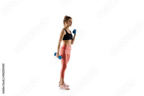 Dumbbells. Young caucasian female model in action, motion isolated on white background with copyspace. Concept of sport, movement, energy and dynamic, healthy lifestyle. Training, practicing.