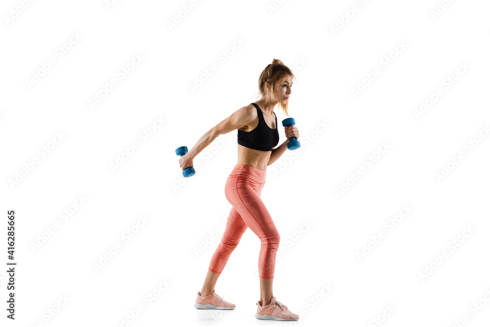 Dumbbells. Young caucasian female model in action, motion isolated on white background with copyspace. Concept of sport, movement, energy and dynamic, healthy lifestyle. Training, practicing. Dumbbells. Young caucasian female model in action, motion isolated on white background with copyspace. Concept of sport, movement, energy and dynamic, healthy lifestyle. Training, practicing.
