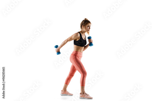 Dumbbells. Young caucasian female model in action, motion isolated on white background with copyspace. Concept of sport, movement, energy and dynamic, healthy lifestyle. Training, practicing. © master1305