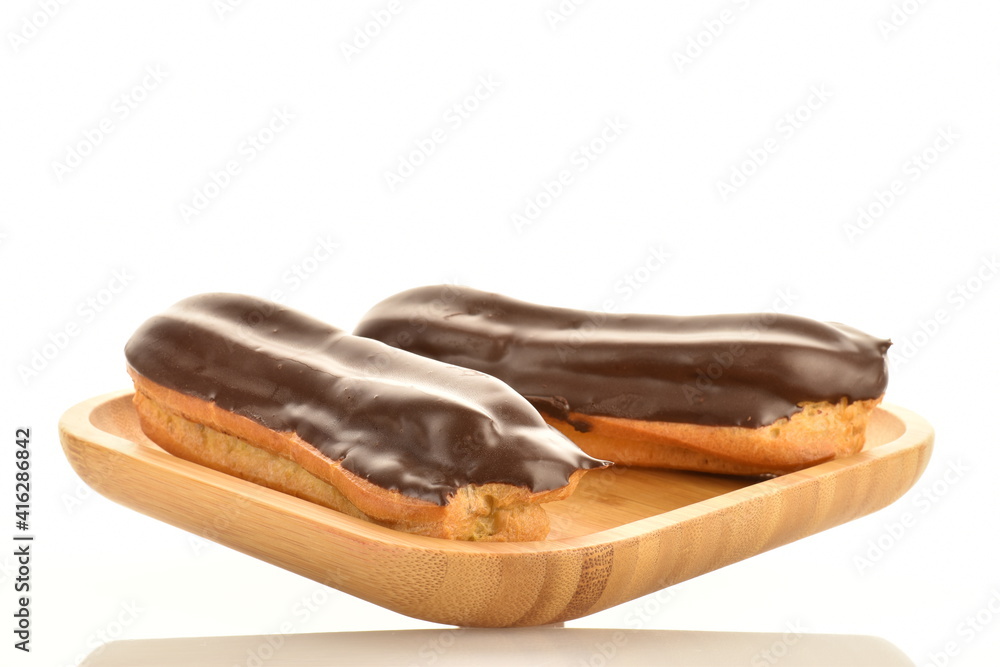 Two sweet chocolate eclairs on a bamboo tray, close-up, isolated on white. Two sweet chocolate eclairs on a bamboo tray, close-up, isolated on white.