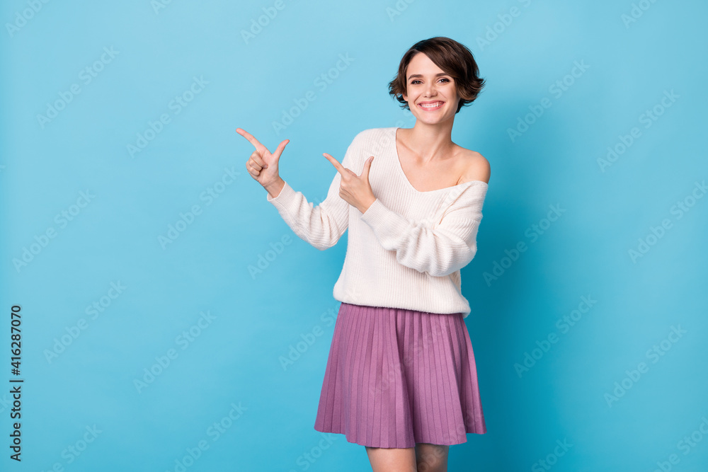 Photo portrait of positive girl pointing two fingers at blank space isolated on pastel blue colored background Photo portrait of positive girl pointing two fingers at blank space isolated on pastel blue colored background