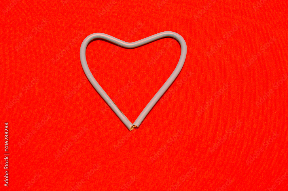 Feast of St. Valentine. Heart made of white wires on a red background. Background, design. Feast of St. Valentine. Heart made of white wires on a red background. Background, design.