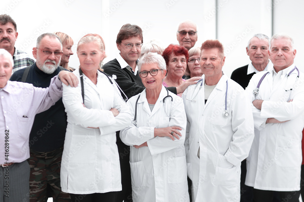 Happy doctors standing in corridor with team at hospital with crossed arms looking at camera Happy doctors standing in corridor with team at hospital with crossed arms looking at camera
