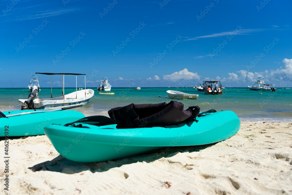 Two kayaks on a Caribbean beach, in the background the sea and moored fishing boats and the blue sky of Mexico, space to write. Two kayaks on a Caribbean beach, in the background the sea and moored fishing boats and the blue sky of Mexico, space to write.