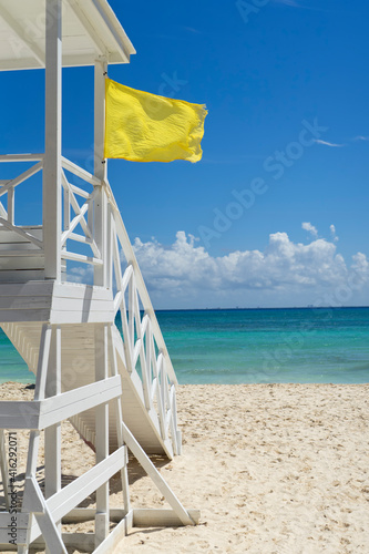 Lifeguard tower with a yellow flag on a tropical beach. In the background the Caribbean Sea and the blue sky in Mexico. Vacation travel concept © Marco B.