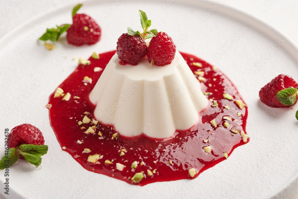 Panna cotta with raspberry syrup, pistachios, berries and mint, high key, close up Panna cotta with raspberry syrup, pistachios, berries and mint, high key, close up