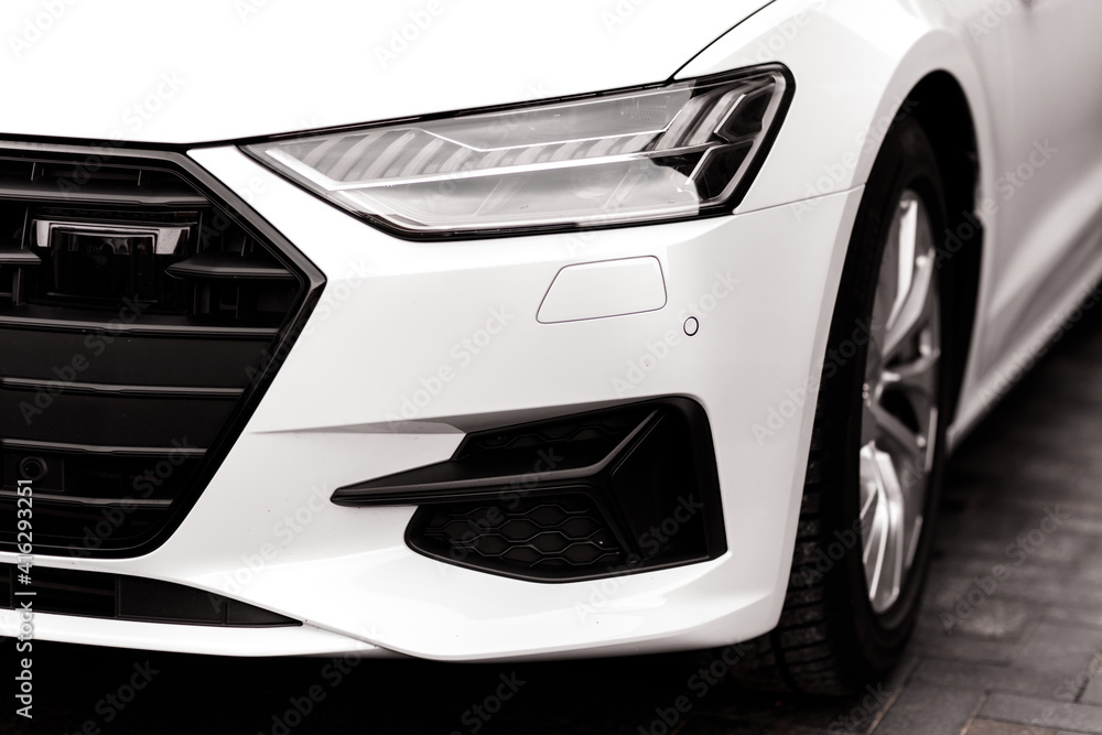 The headlamp of the new clean white sports car is of aggressive form with a part of the bonnet and black wheel, bumper