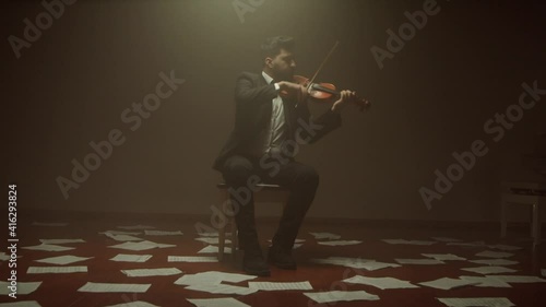 violinist playing the violin alone on stage,notes on the floor