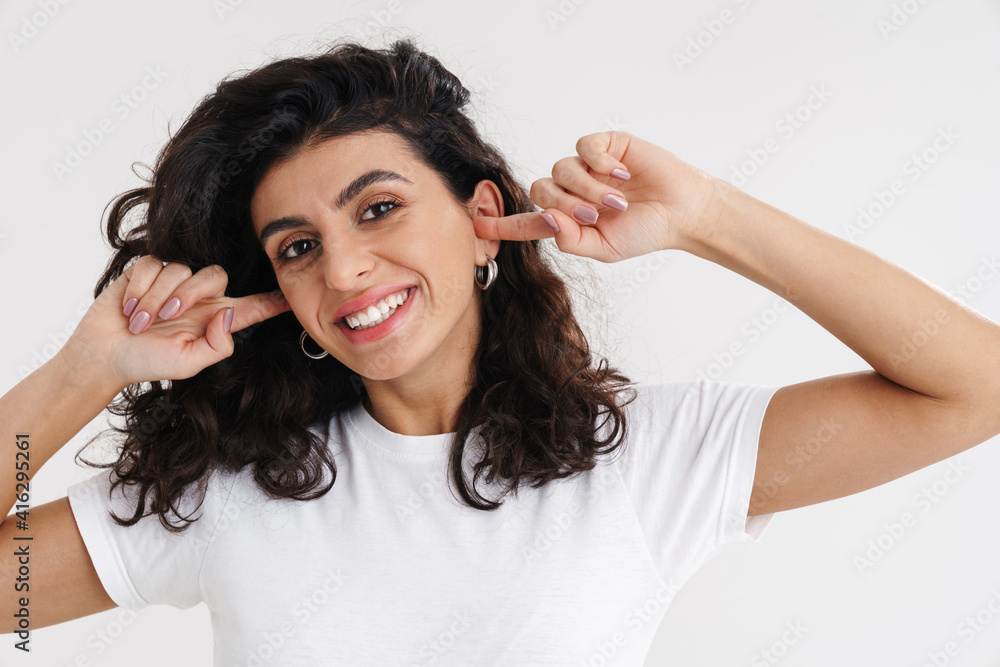 Fototapeta premium Cheerful young brunette woman covers ears isolated