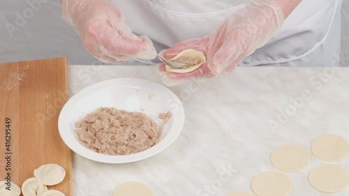 A woman sculpts homemade dumplings, puts minced meat on the dough. Making homemade dumplings. Close-up.
