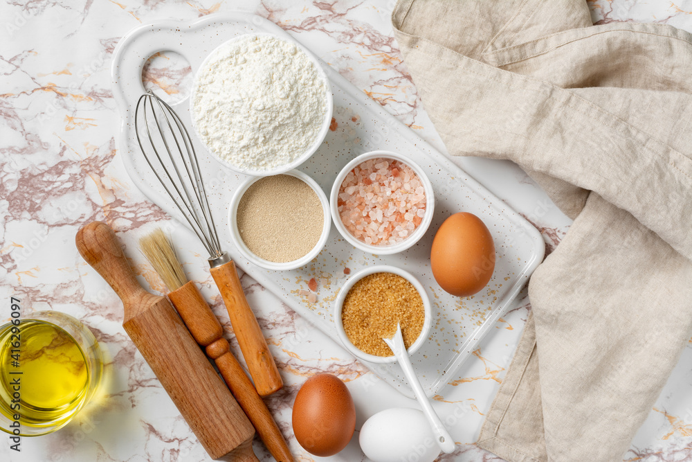 Ingredients for baking on a culinary background. Eggs, flour, dry yeast, sugar, salt on the kitchen table. The concept of preparation for yeast baking. Top view Ingredients for baking on a culinary background. Eggs, flour, dry yeast, sugar, salt on the kitchen table. The concept of preparation for yeast baking. Top view