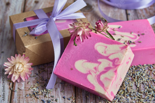 Fragrant pink organic handmade soap, gift box decorated with silk ribbon and dried flowers on the wooden countertop.