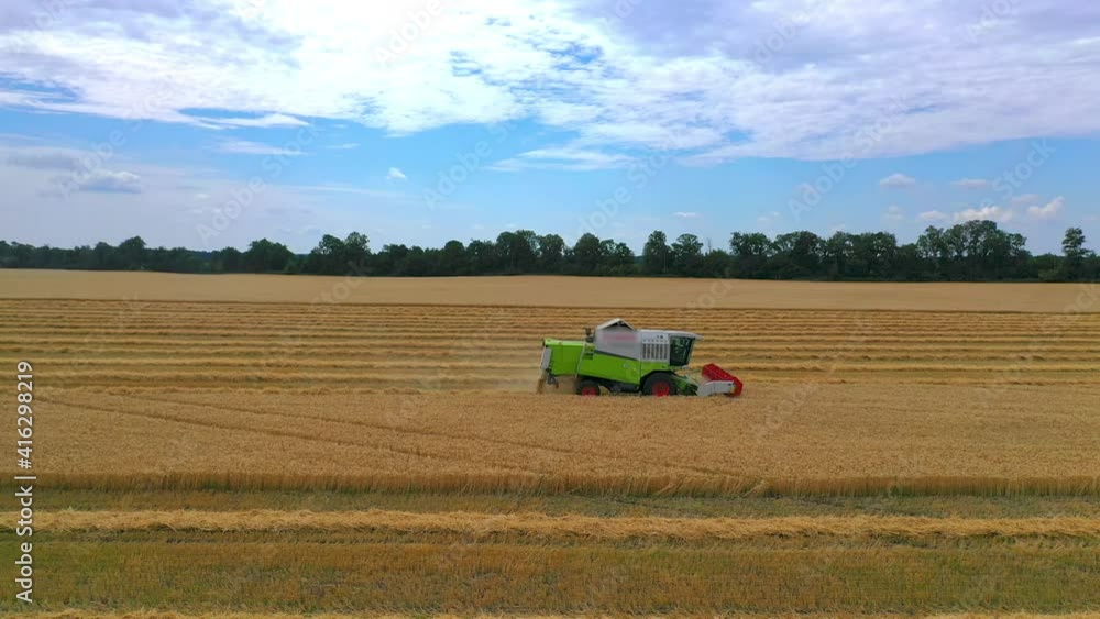 Green grain harvesting combine in a sunny day. Yellow field with grain. Agricultural technic works in field. Closeup. Green grain harvesting combine in a sunny day. Yellow field with grain. Agricultural technic works in field. Closeup.