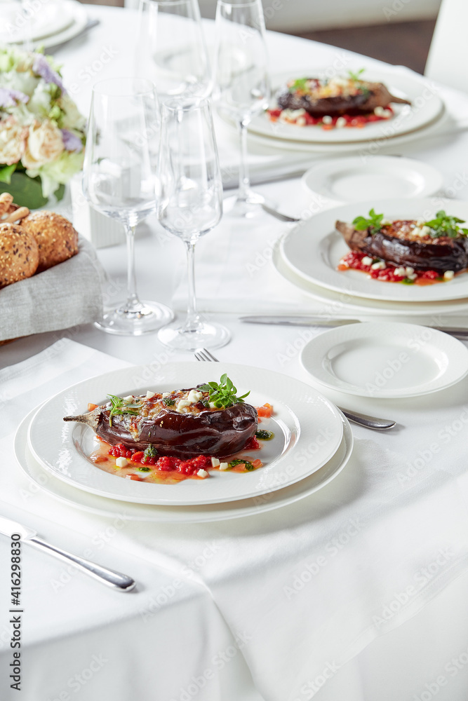 Half baked eggplants with meat, cheese and tomatoes on white background. Banquet festive dishes. Gourmet restaurant menu. White background. Half baked eggplants with meat, cheese and tomatoes on white background. Banquet festive dishes. Gourmet restaurant menu. White background.
