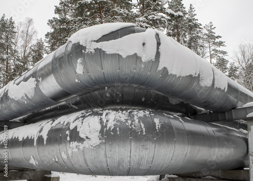 Huge industrial pipelines of central heating system. Snow on pipes. photo