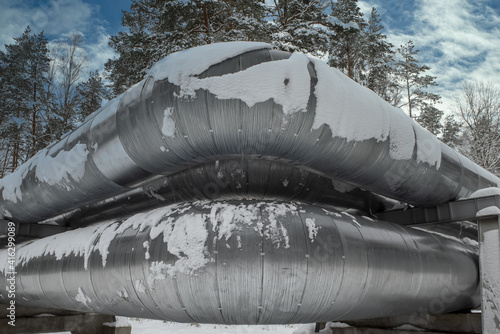 Huge industrial pipelines of central heating system. Snow on pipes. photo