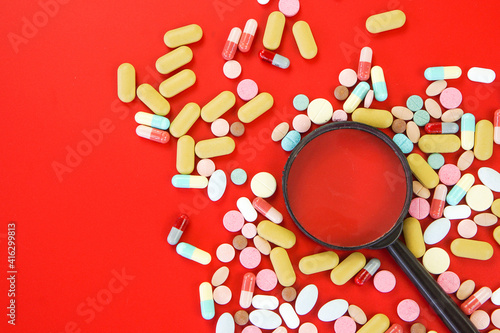 Pile of medical capsules pills in red and white color on red background, top view for copy space
