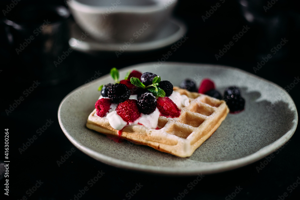 Belgian waffles with wild berries and cream cheese on a dark background Belgian waffles with wild berries and cream cheese on a dark background