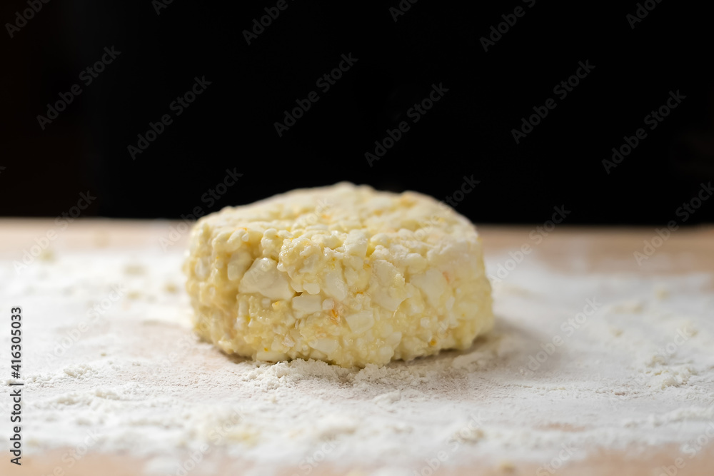 Cottage cheese pancakes on a wooden board with flour close up in the background black background with copy space