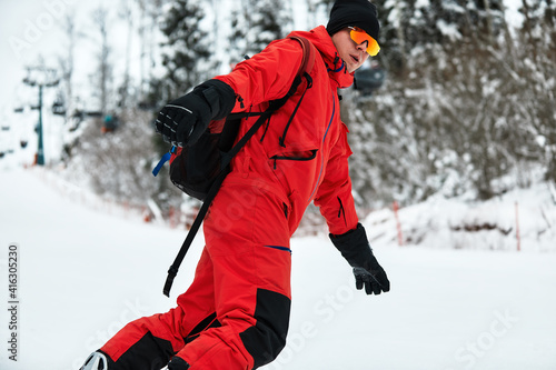 Male snowboarder in a red suit rides on the snowy hill with snowboard, Skiing and snowboarding concept